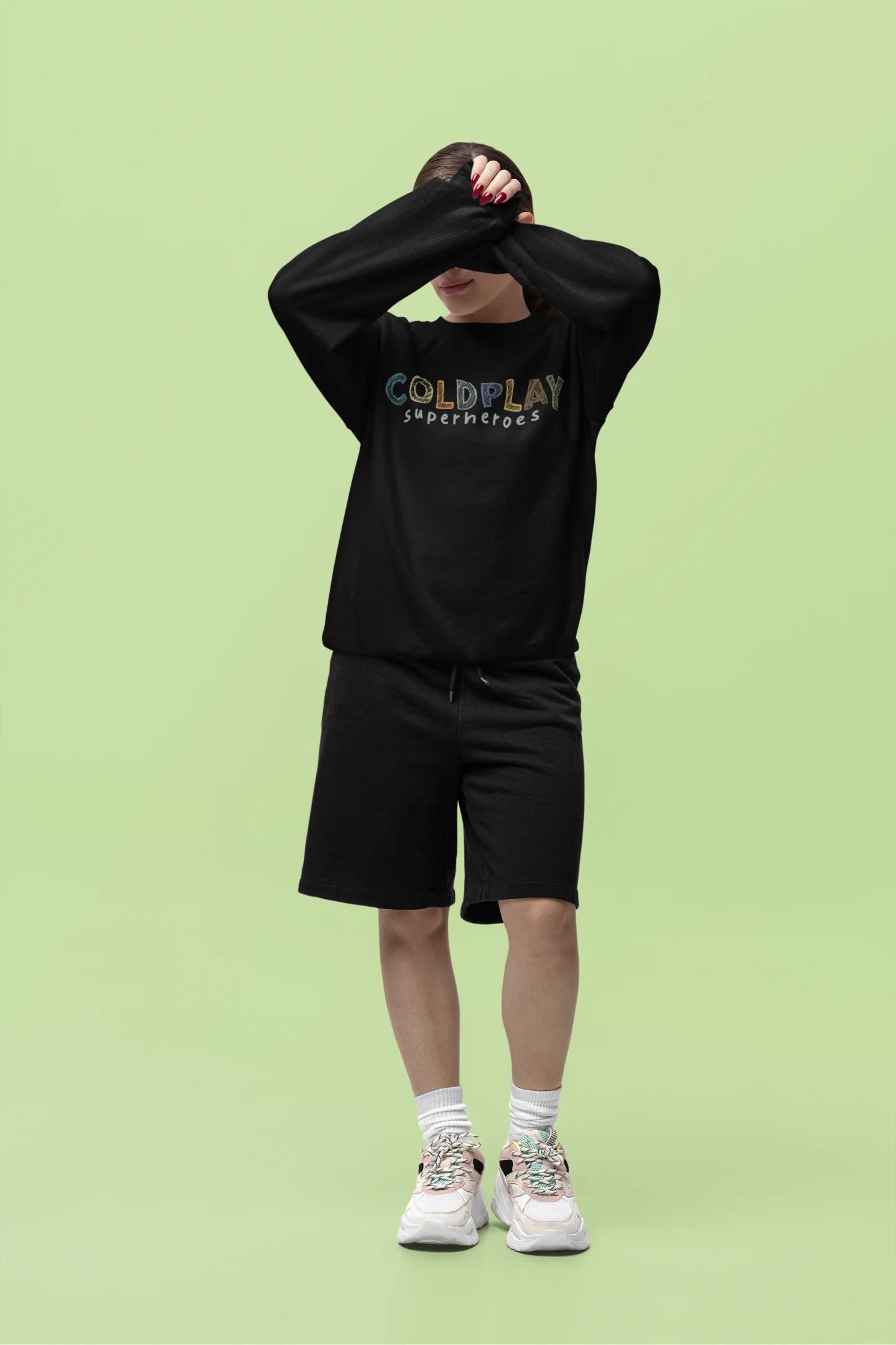Fourth front view of a female model wearing an black sweatshirt with a design inspired by the "Something Just Like This" music video, featuring the word "Superheroes".