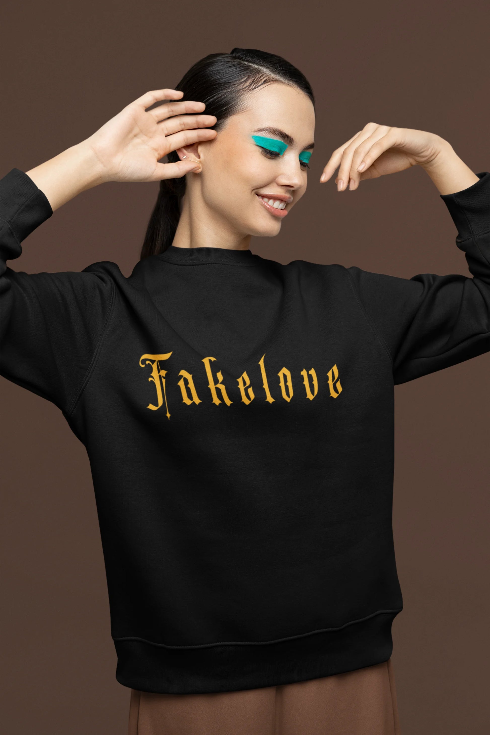 Second front view of a female model wearing a black sweatshirt with a brutalist design featuring a fallen angel statue and the phrase "Fake Love".