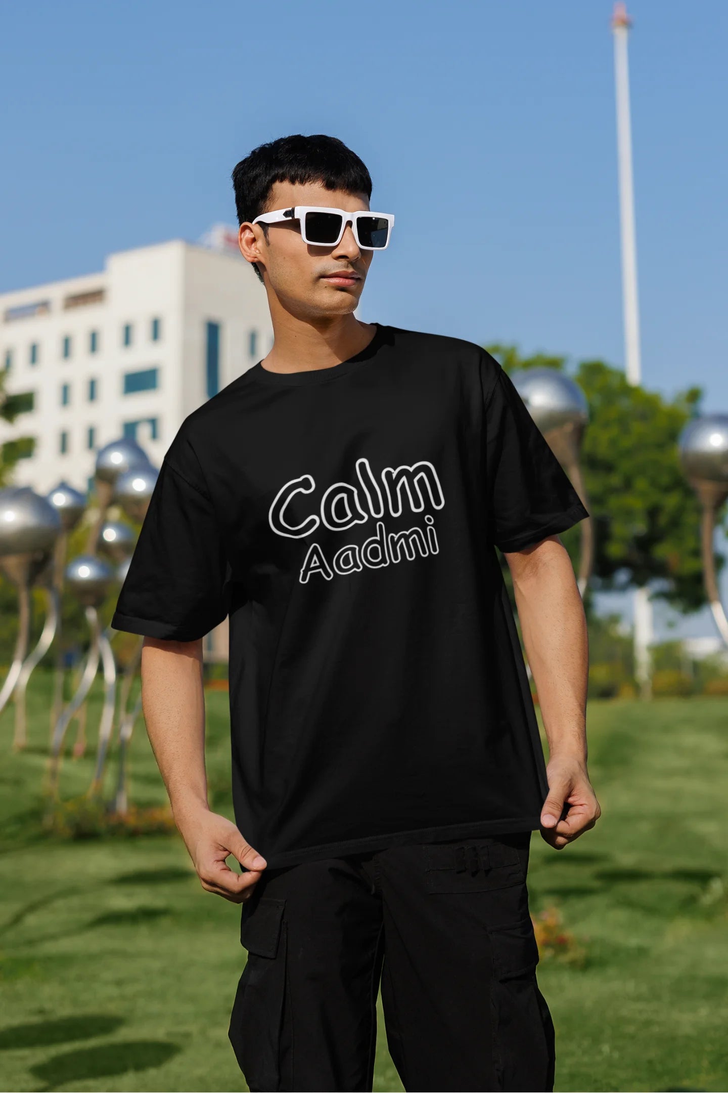 Front view of the man of the couple wearing matching black oversize tees, one with "Calm one" and the other with "Chaotic one" printed on them in Hindi.