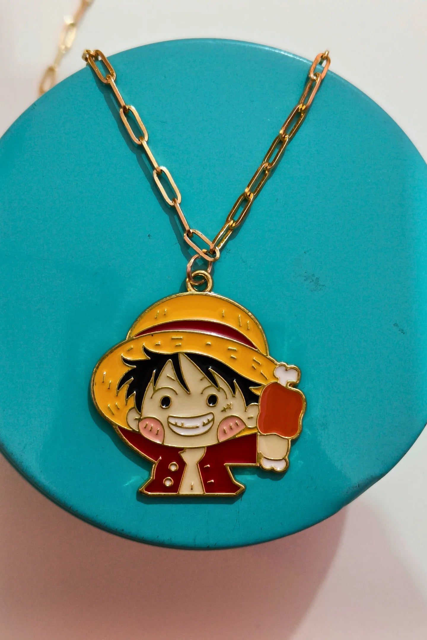 First view of a gold chain necklace with a small pendant depicting Luffy from One Piece eating meat.