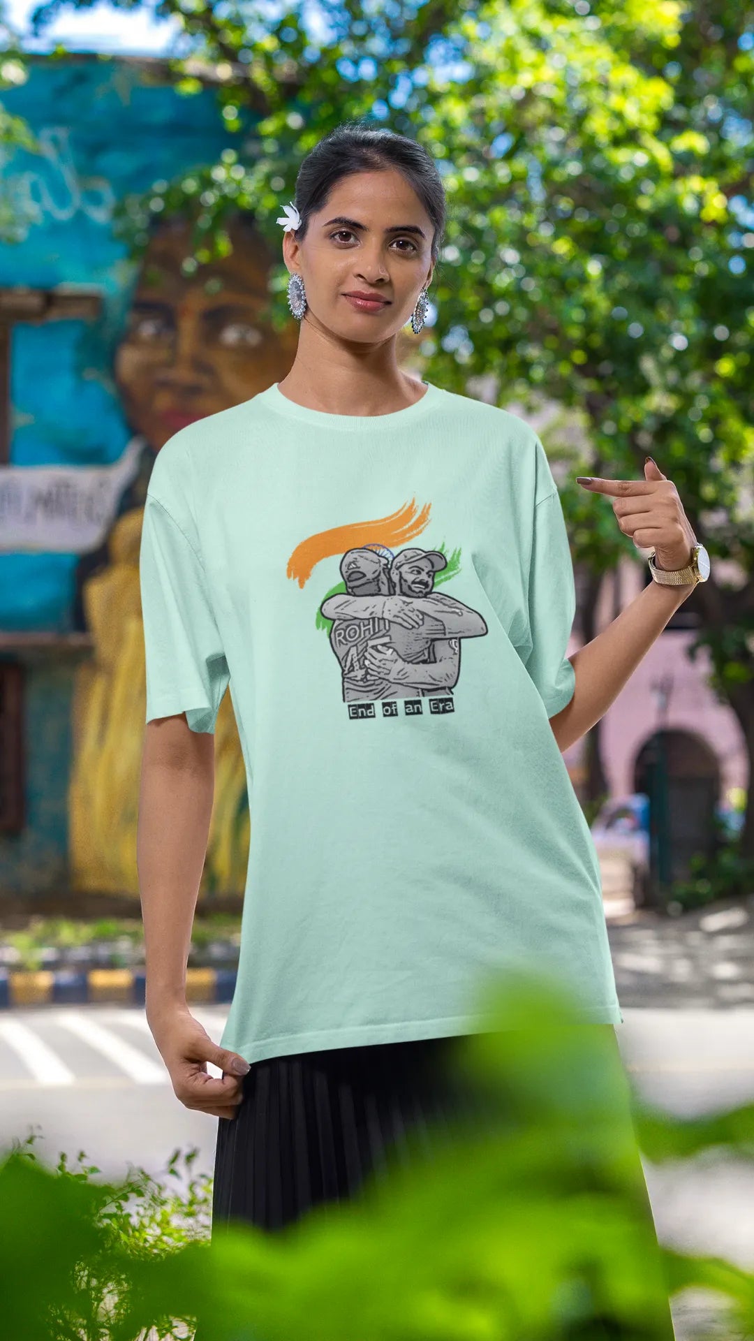 Third front view of a female model wearing an mint green oversized t-shirt featuring a photo of Virat Kohli and Rohit Sharma in a celebratory hug after the World Cup 2024 final. Ideal for Indian cricket fans who want to honor the team's victory and potentially a changing of the guard.