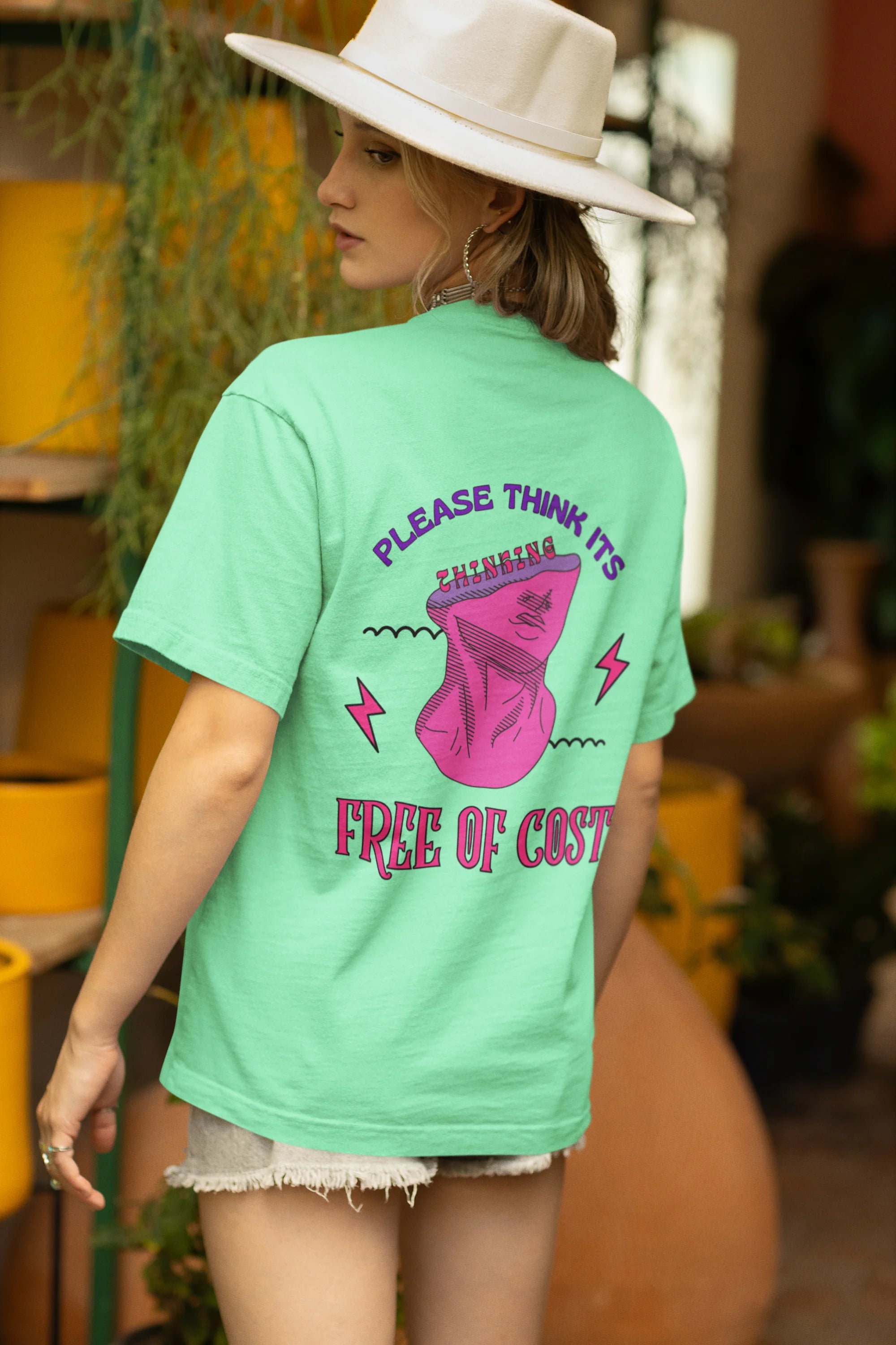 Back view of a female model wearing an mint green oversized t-shirt featuring a thought-provoking design of a man's bust with the text "Think It's Free of Cost." Ideal for those who love funny clothing and the importance of mindful communication.