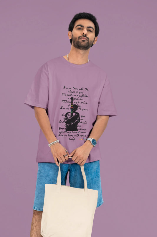 2nd front view of a male model wearing a dirty purple oversized t-shirt featuring a design inspired by Ed Sheeran's concerts, related to the song "Shape of You."