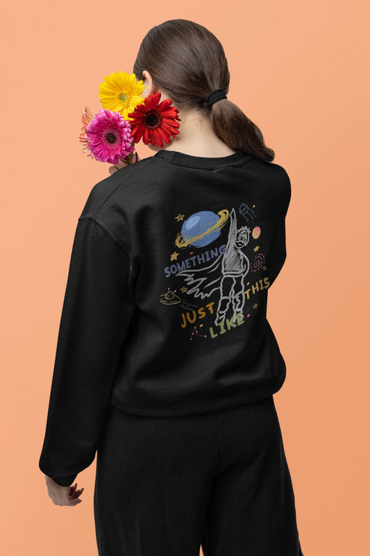 Back view of a female model wearing an black sweatshirt with a design inspired by the "Something Just Like This" music video, featuring the word "Superheroes".