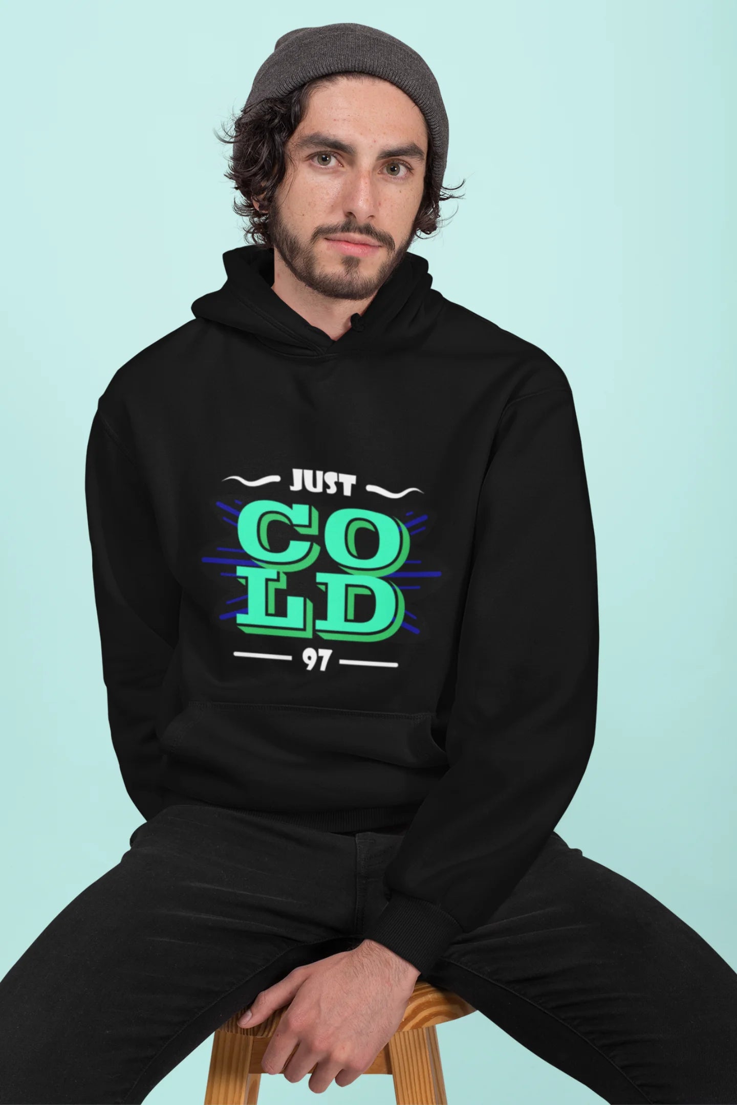 3rd front view of a male model wearing an black sweatshirt with the text "Just Cold" printed on it.