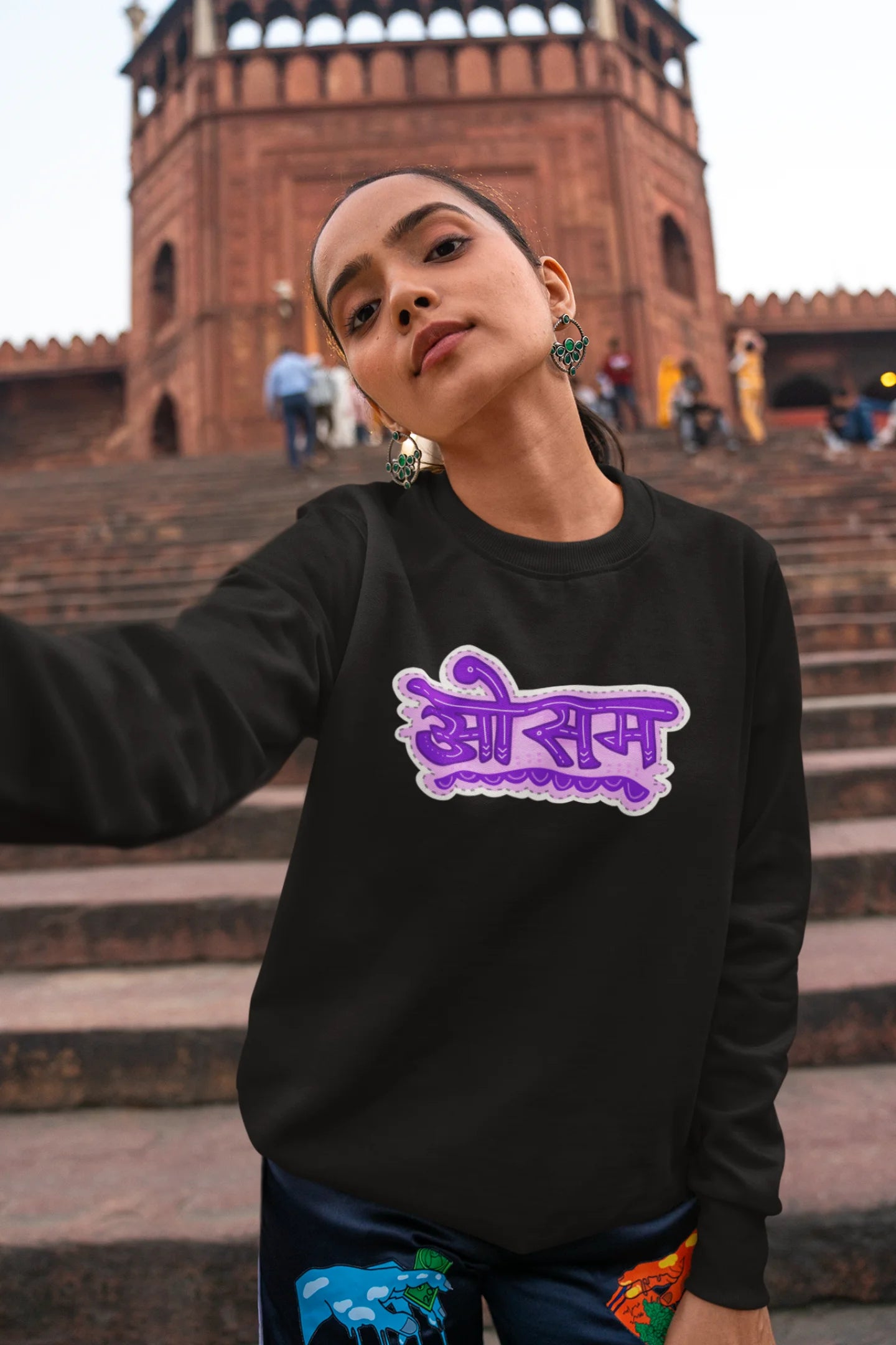 5th front view of a female model wearing a black colored oversized graphic t-shirt featuring the word "awesome" in a Hindi script.