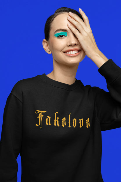 Fifth front view of a female model wearing a black sweatshirt with a brutalist design featuring a fallen angel statue and the phrase "Fake Love".