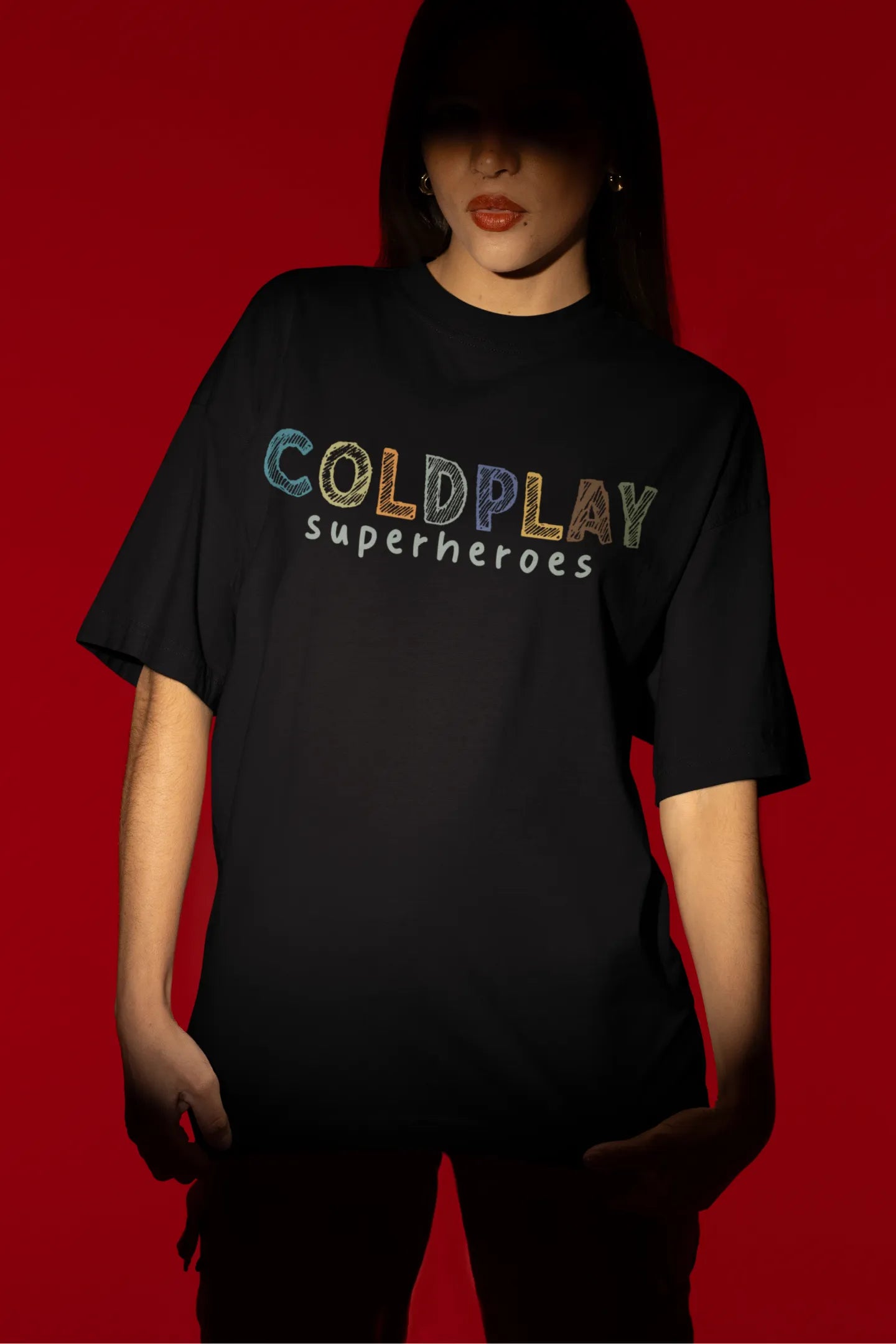 First view of a female model wearing an black oversized t-shirt with a design inspired by the "Something Just Like This" music video, featuring the word "Superheroes".