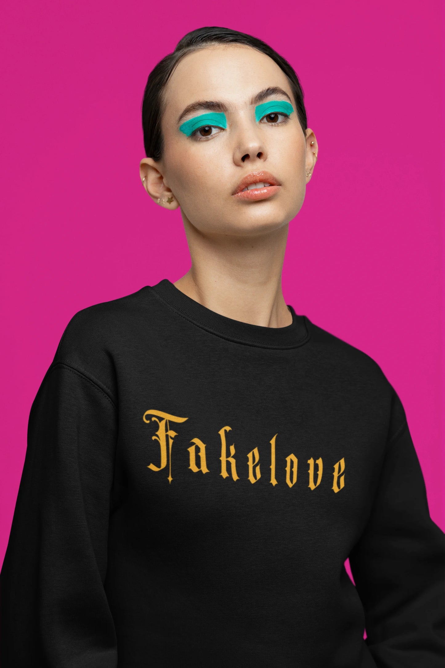 Third front view of a female model wearing a black sweatshirt with a brutalist design featuring a fallen angel statue and the phrase "Fake Love".