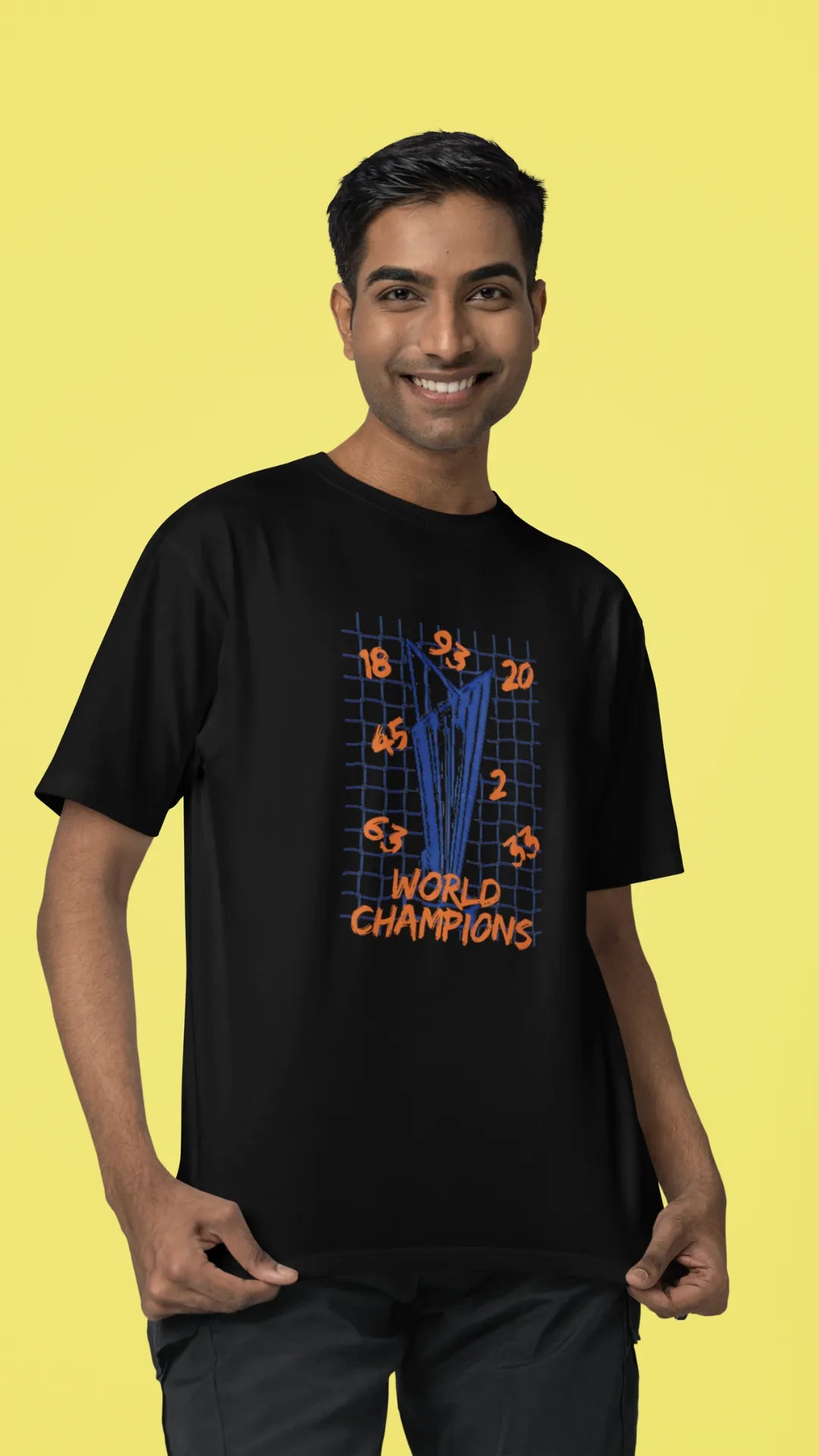 Third front image of male model wearing a black oversized t-shirt featuring the World Cup 2024 trophy with the text "World Champions" underneath. Ideal for Indian cricket fans celebrating their team's victory.