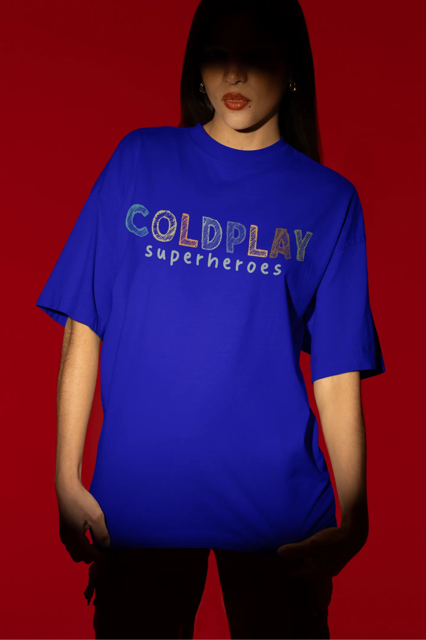 First view of a female model wearing an royal blue oversized t-shirt with a design inspired by the "Something Just Like This" music video, featuring the word "Superheroes".