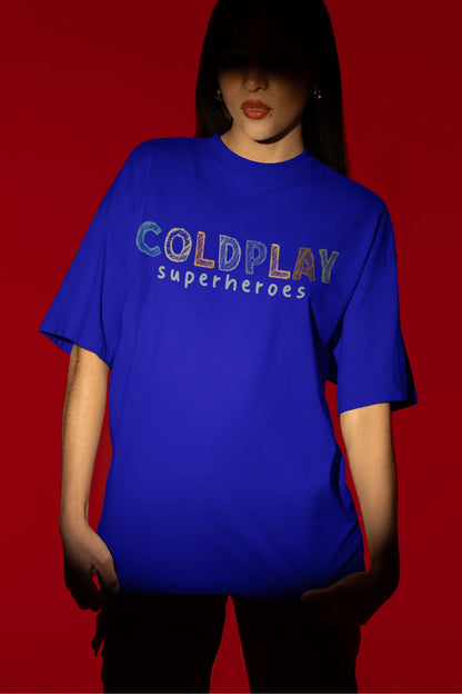 First view of a female model wearing an royal blue oversized t-shirt with a design inspired by the "Something Just Like This" music video, featuring the word "Superheroes".
