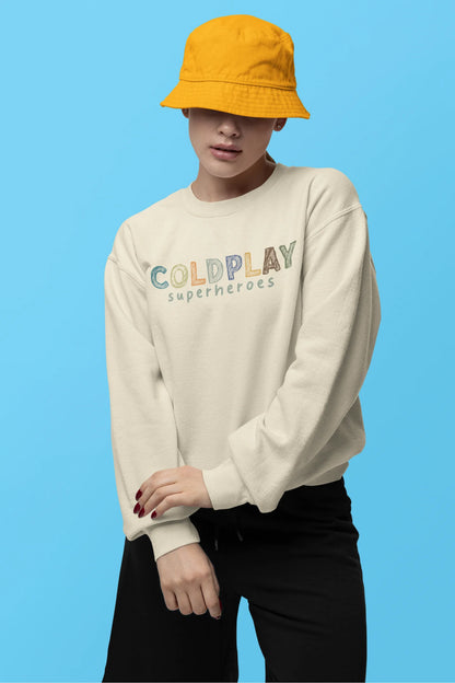 First front view of a female model wearing an cream sweatshirt with a design inspired by the "Something Just Like This" music video, featuring the word "Superheroes".
