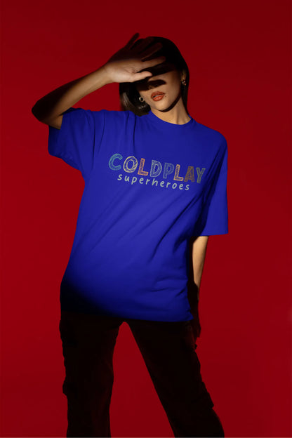 Fourth view of a female model wearing an royal blue oversized t-shirt with a design inspired by the "Something Just Like This" music video, featuring the word "Superheroes".