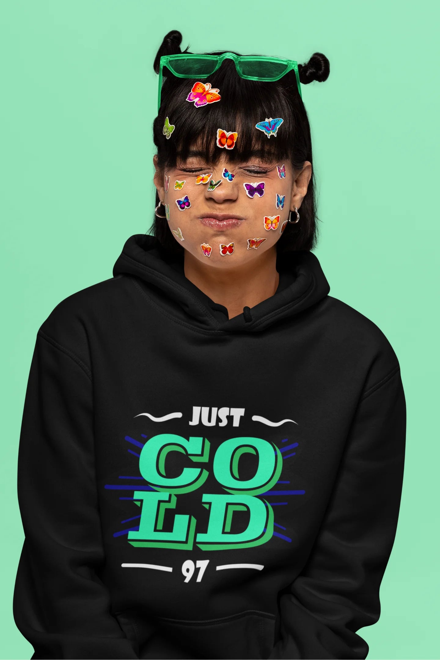 6th front view of a female model wearing an black sweatshirt with the text "Just Cold" printed on it.