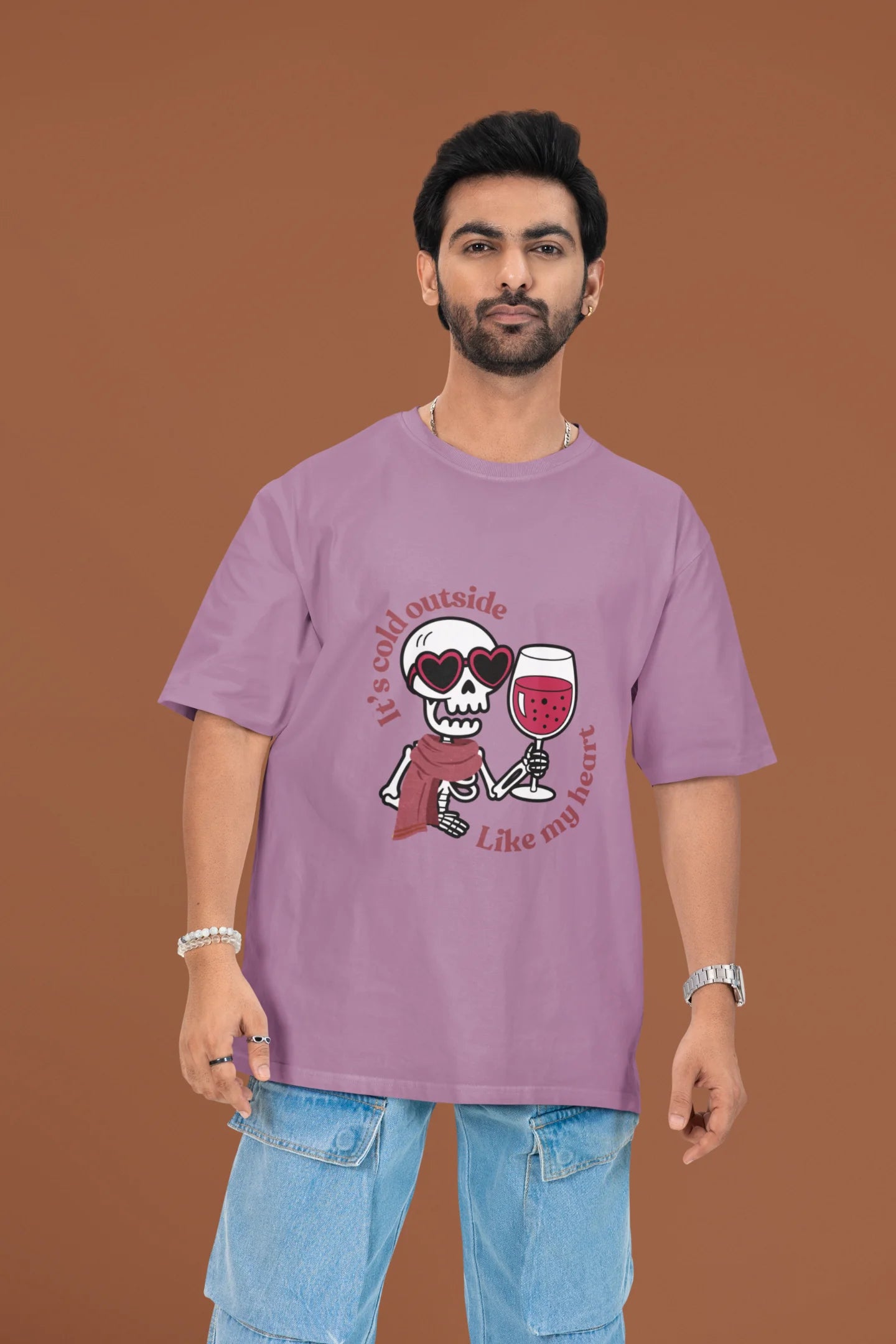 3rd front image of a male model wearing a dirty purple oversized t-shirt with the text "Cold Outside Like My Heart" and a design of a skeleton drinking champagne.