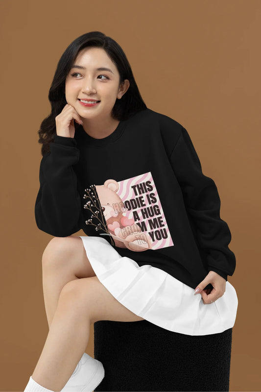 2nd front view of a female model wearing a black sweatshirt with a heartwarming design of a teddy bear offering a hug, offering a comforting and relaxing aesthetic.