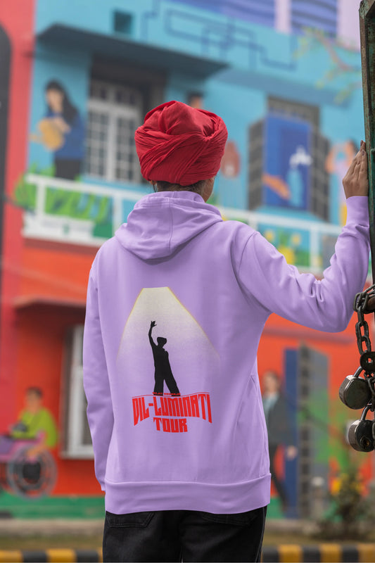 Back view of a female model wearing a dirty purple hoodie with a portrait of Diljit Dosanjh on stage, illuminated by a spotlight.