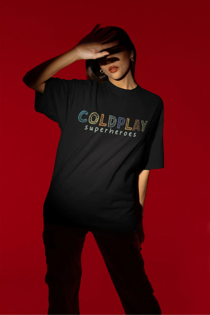 Third view of a female model wearing an black oversized t-shirt with a design inspired by the "Something Just Like This" music video, featuring the word "Superheroes".
