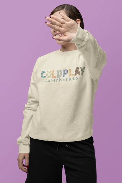 Third front view of a female model wearing an cream sweatshirt with a design inspired by the "Something Just Like This" music video, featuring the word "Superheroes".