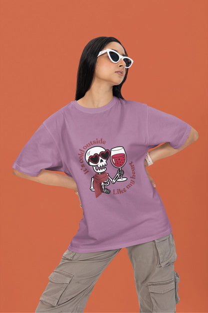 2nd front image of a female model wearing a dirty purple oversized t-shirt with the text "Cold Outside Like My Heart" and a design of a skeleton drinking champagne.