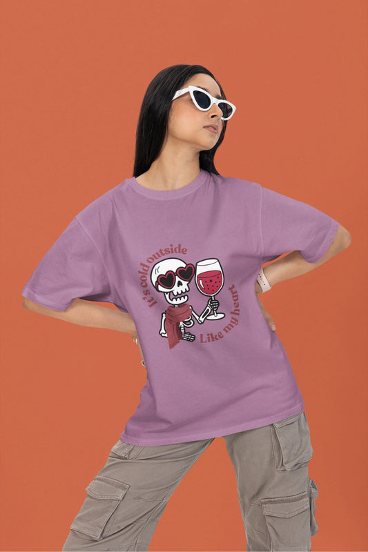 2nd front image of a female model wearing a dirty purple oversized t-shirt with the text "Cold Outside Like My Heart" and a design of a skeleton drinking champagne.