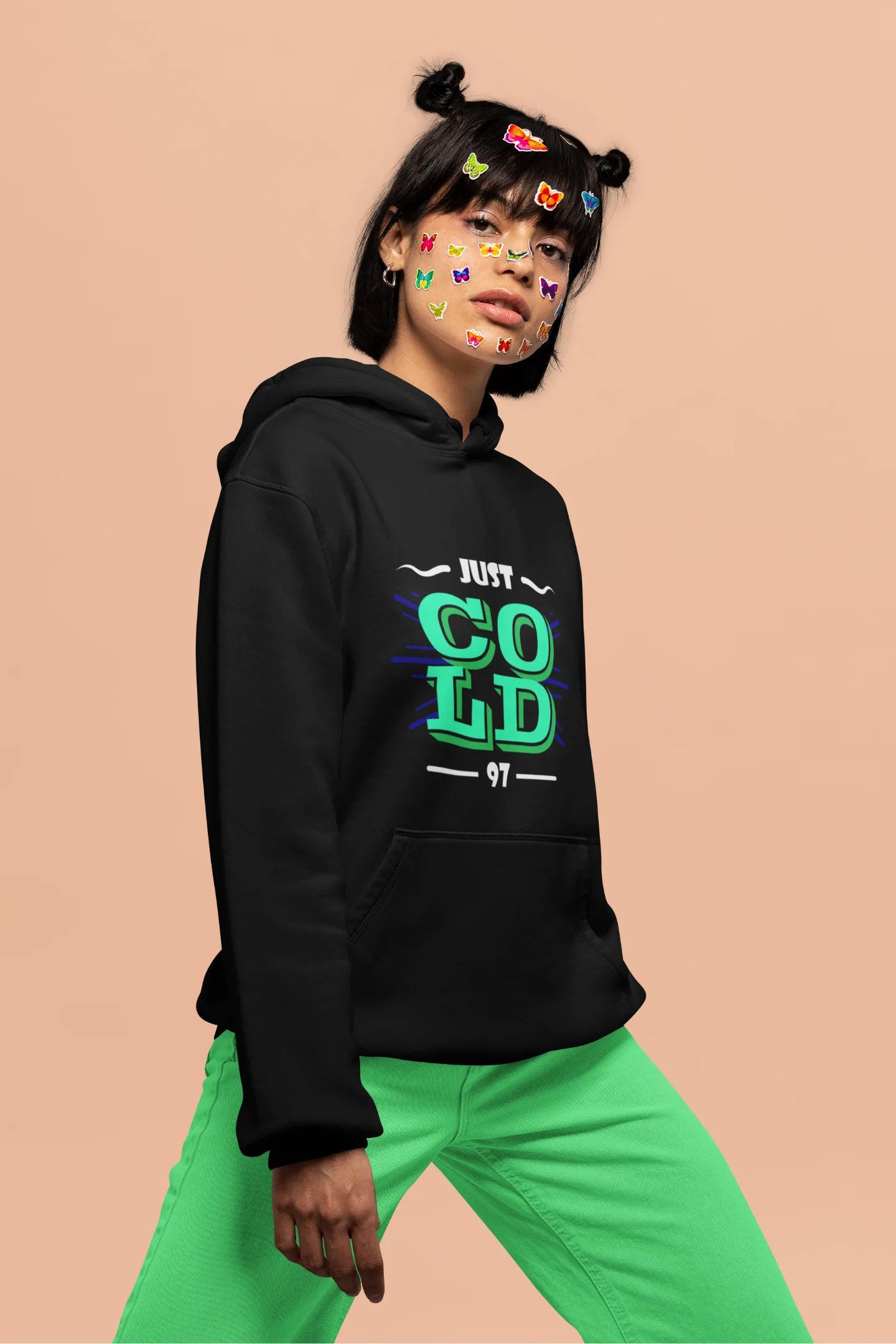 3rd front view of a female model wearing an black sweatshirt with the text "Just Cold" printed on it.