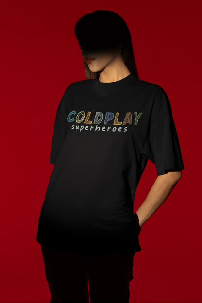 Second view of a female model wearing an black oversized t-shirt with a design inspired by the "Something Just Like This" music video, featuring the word "Superheroes".