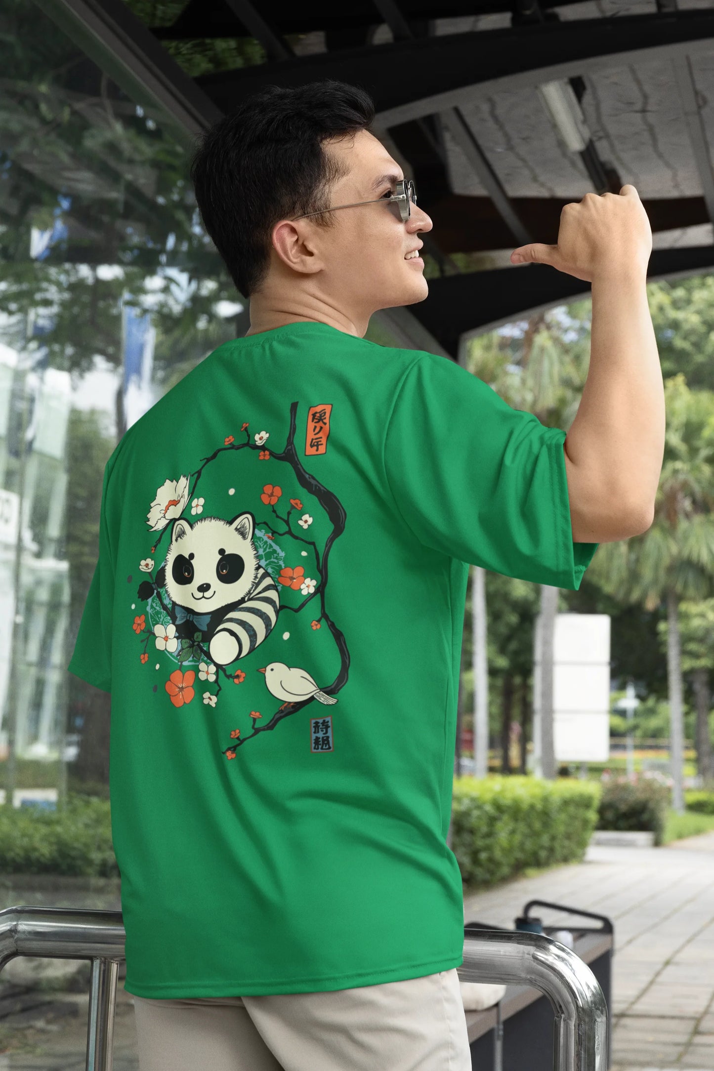 Back view of a male model wearing a forest green oversized tee with a panda fox surrounded by bamboo.