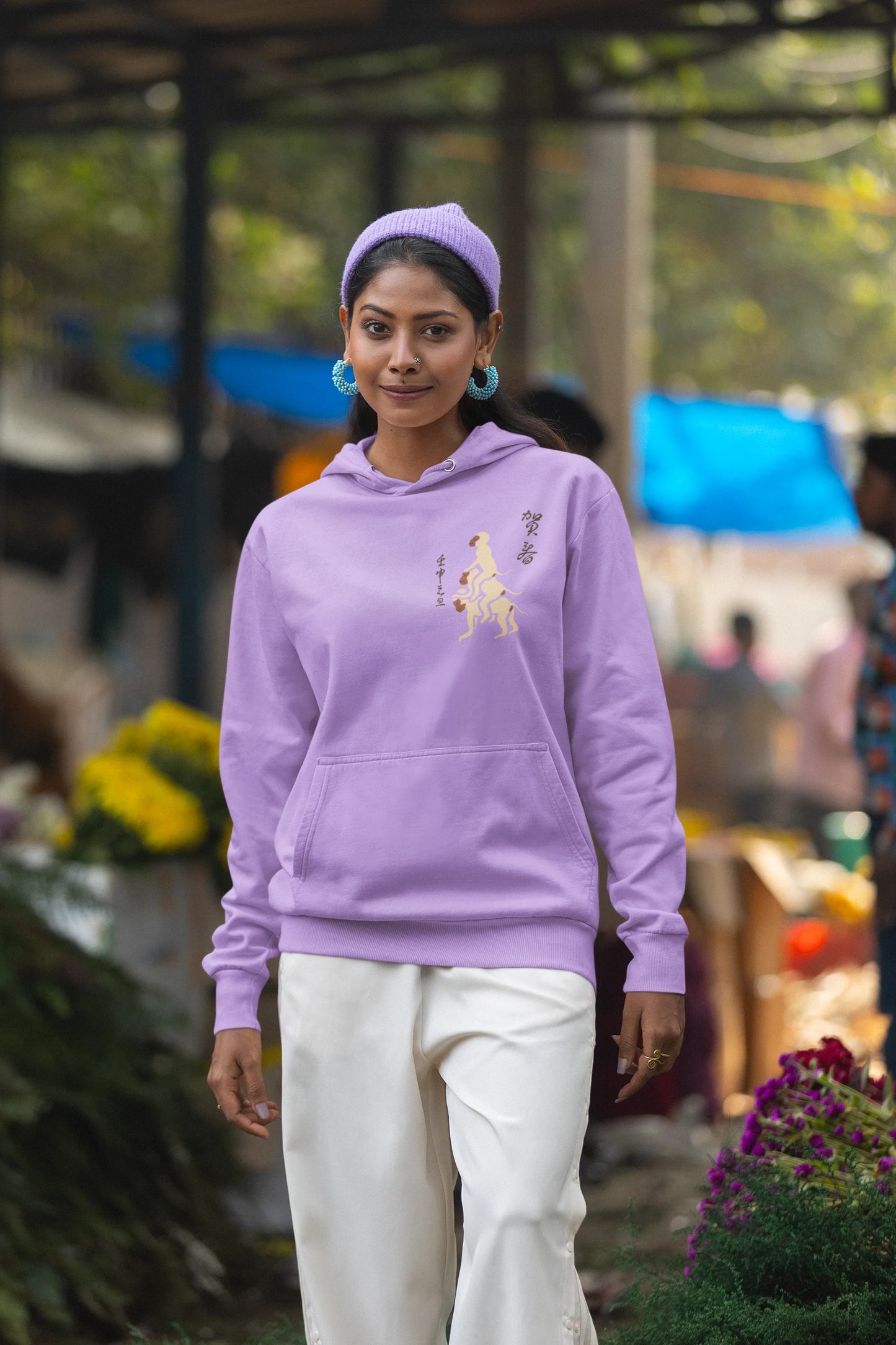 First front view of a female model wearing a lavender hoodie with a design of the three wise monkeys: "See no evil, hear no evil, speak no evil."