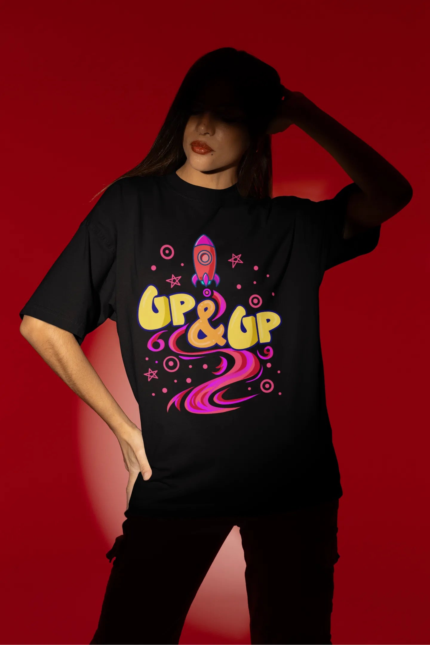 Third front view of a female model wearing an black oversized t-shirt with a rocket ship design and the text "Up & Up".