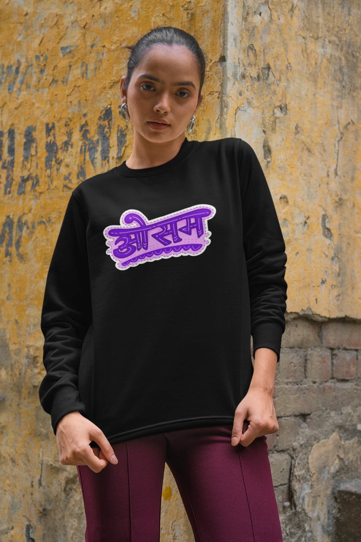 3rd front view of a female model wearing a black colored oversized graphic t-shirt featuring the word "awesome" in a Hindi script.