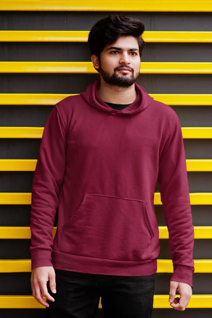 Second front view of a male model wearing a maroon hoodie with a design of a wildcat sitting on ocean waves.