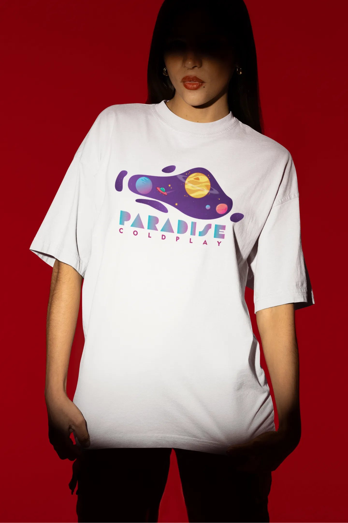 Second front view of a female model wearing an white oversized t-shirt with the "Paradise" album artwork by Coldplay.
