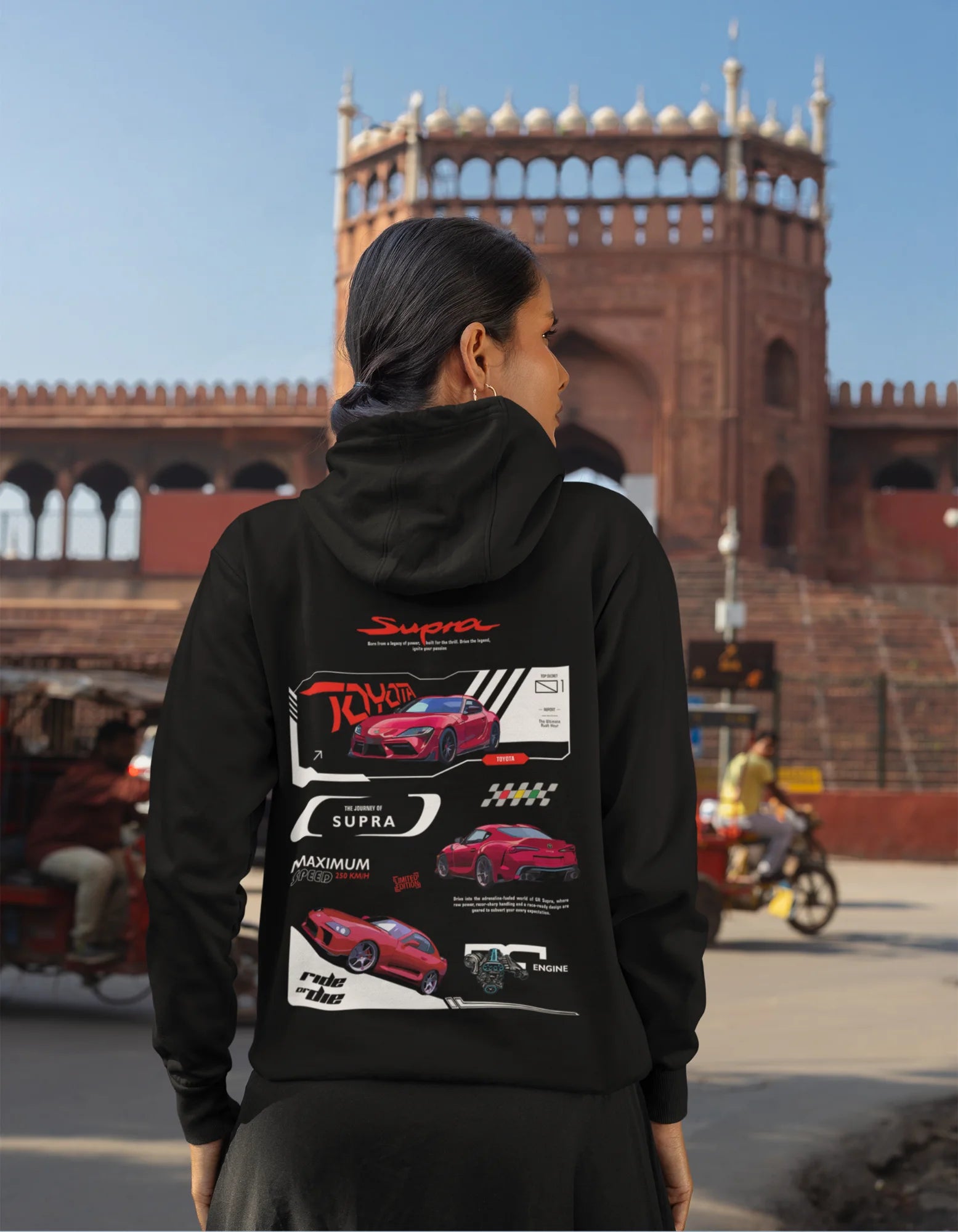 Back view of a female model wearing a black hoodie featuring a Toyota Supra design, exuding speed and power.