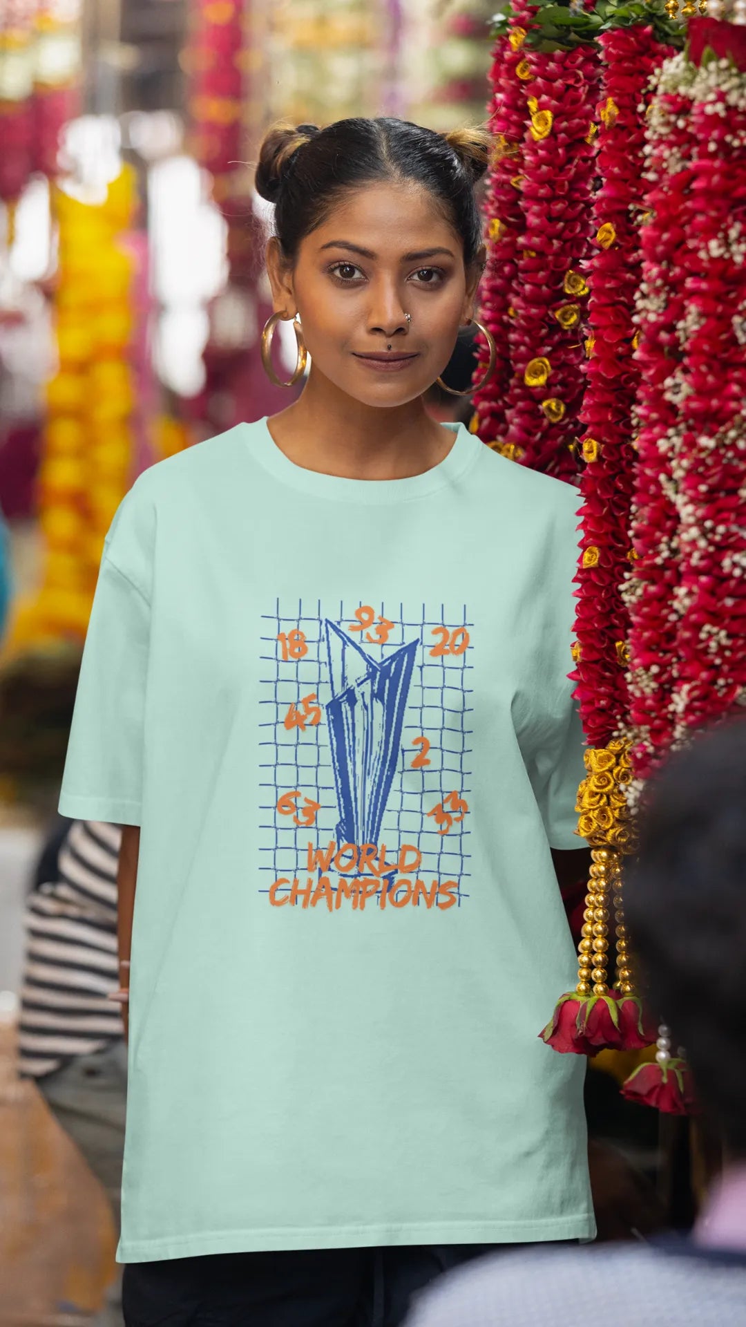 First front image of female model wearing a mint green oversized t-shirt featuring the World Cup 2024 trophy with the text "World Champions" underneath. Ideal for Indian cricket fans celebrating their team's victory.