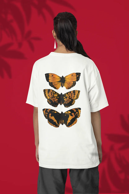 Back view of a female model wearing a off-white oversized tee with a design featuring three different types of butterflies, symbolizing the beauty and diversity of nature.