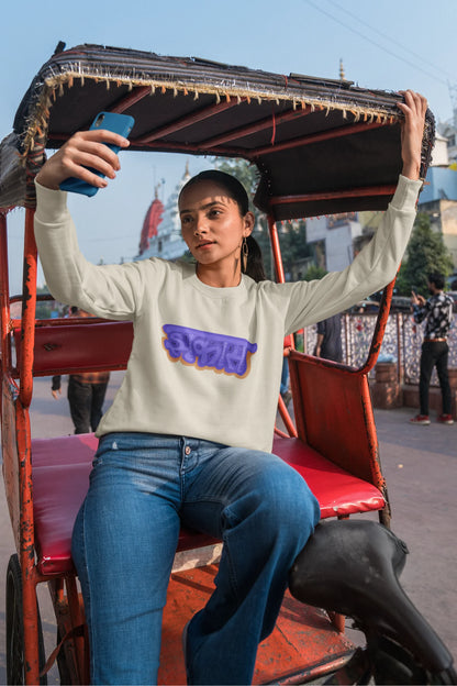 First front view of a female model wearing an cream sweatshirt featuring "Jhakas" in a stylish font.