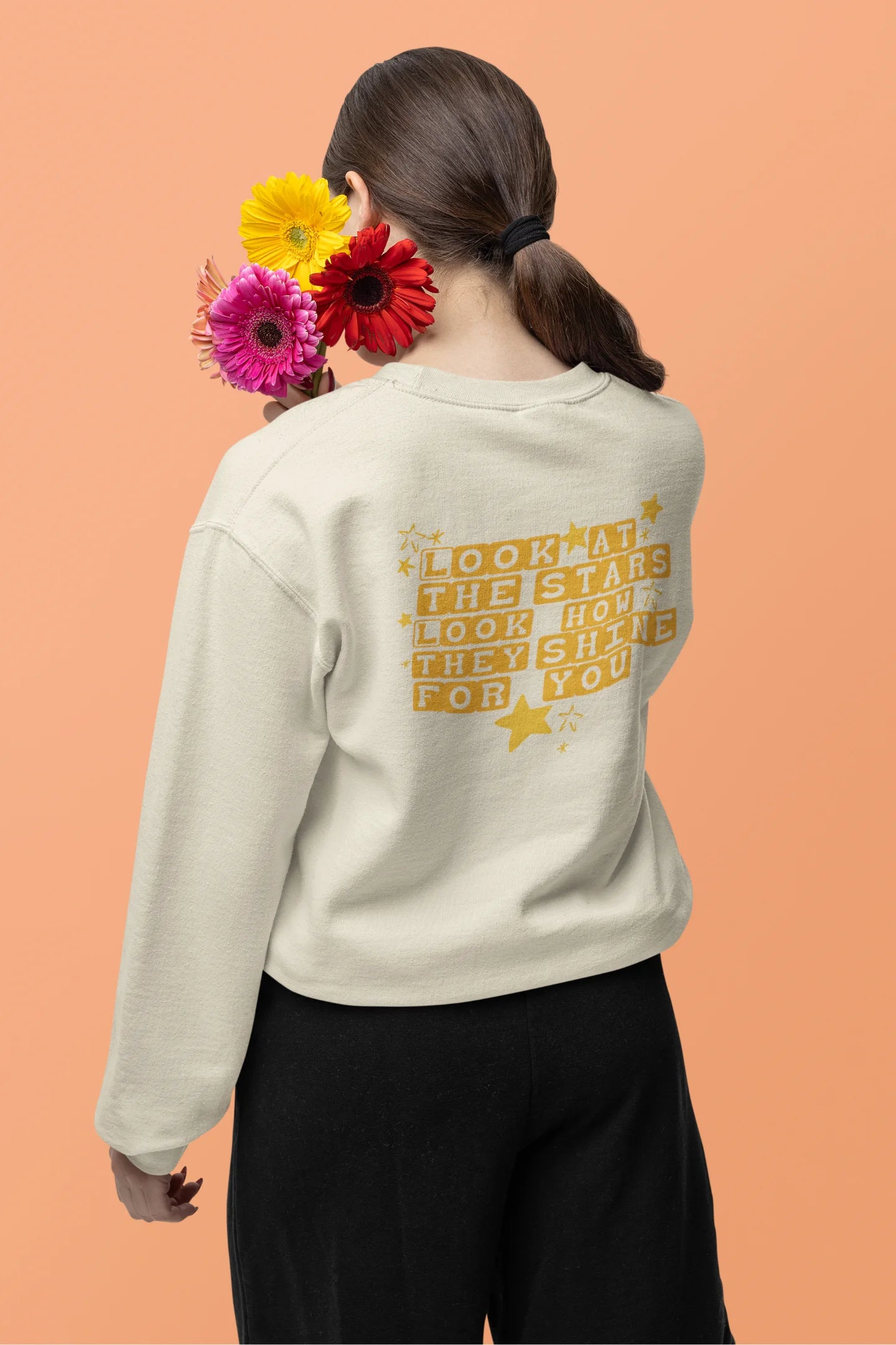 Back view of a female model wearing a cream sweatshirt with the "Yellow" album artwork by Coldplay.