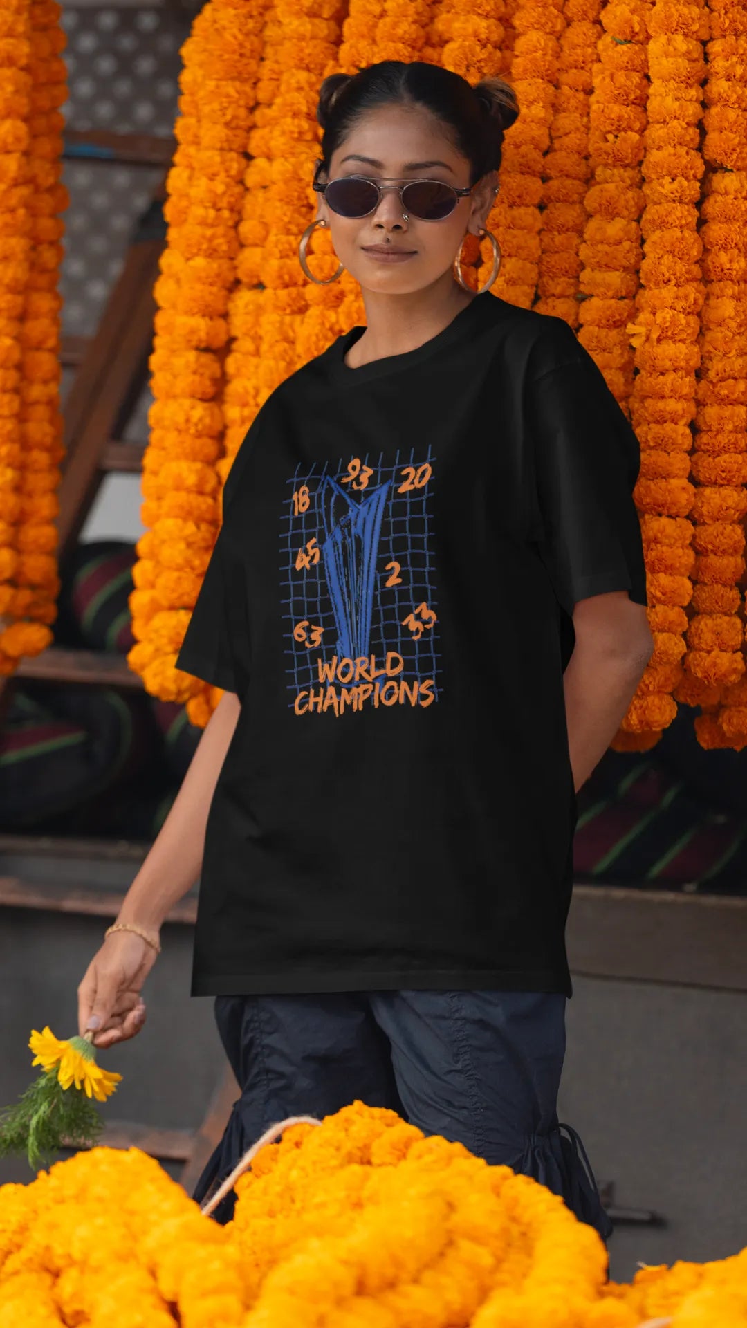 First front image of female model wearing a black oversized t-shirt featuring the World Cup 2024 trophy with the text "World Champions" underneath. Ideal for Indian cricket fans celebrating their team's victory.