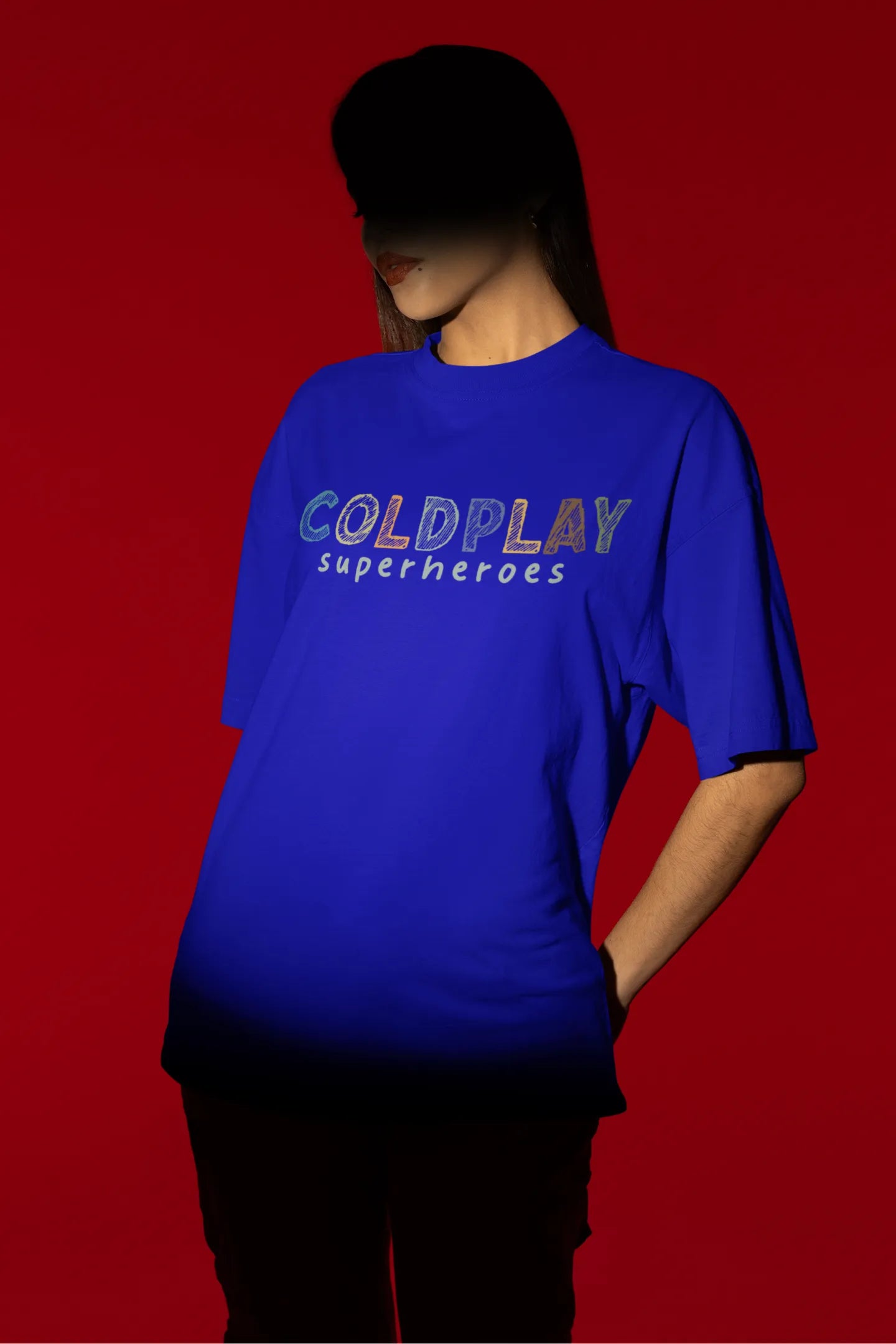 Second view of a female model wearing an royal blue oversized t-shirt with a design inspired by the "Something Just Like This" music video, featuring the word "Superheroes".