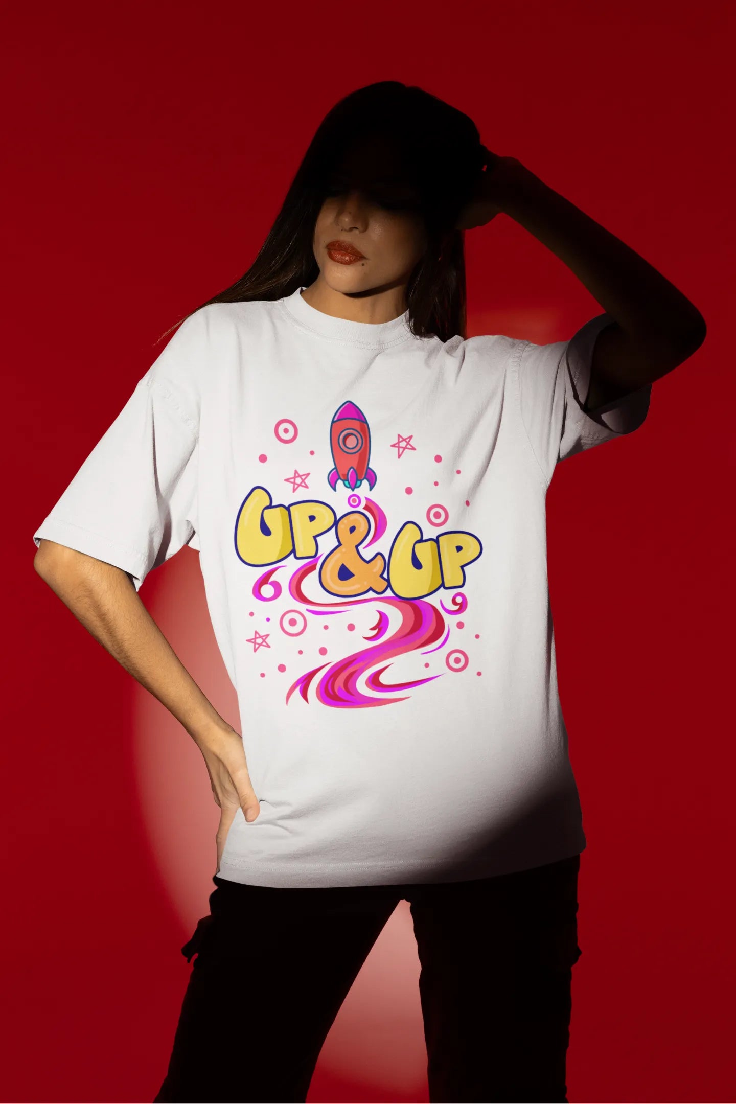 Fourth front view of a female model wearing an off-white oversized t-shirt with a rocket ship design and the text "Up & Up".