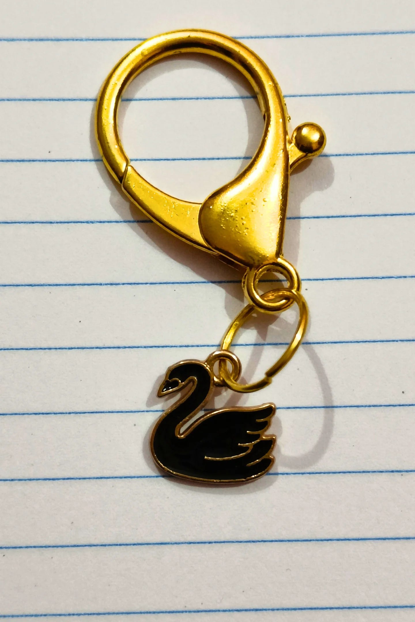 A couples keychain featuring two separate charms: one of a black swan 