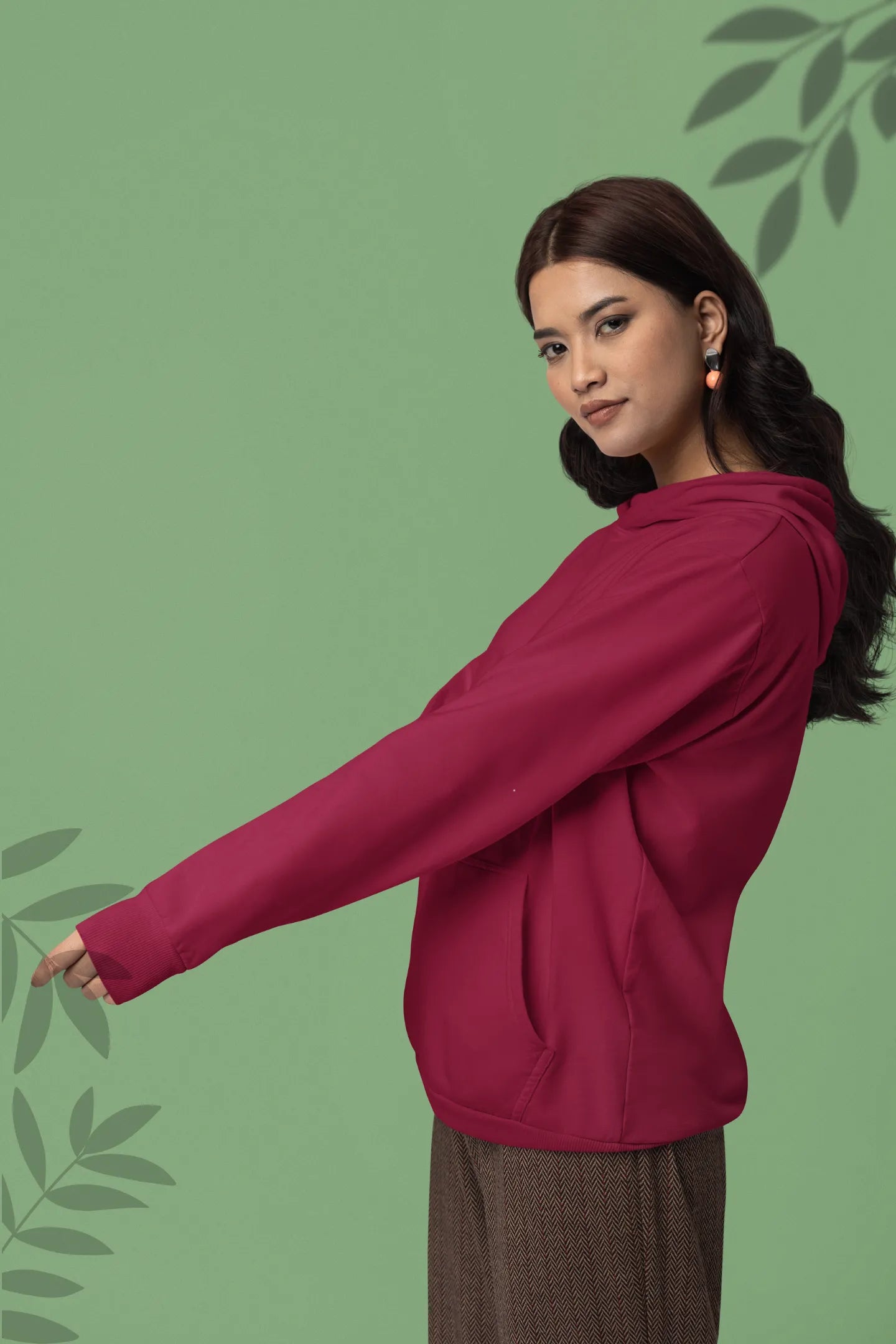 Third front view of a female model wearing a maroon hoodie with a design of a wildcat sitting on ocean waves.