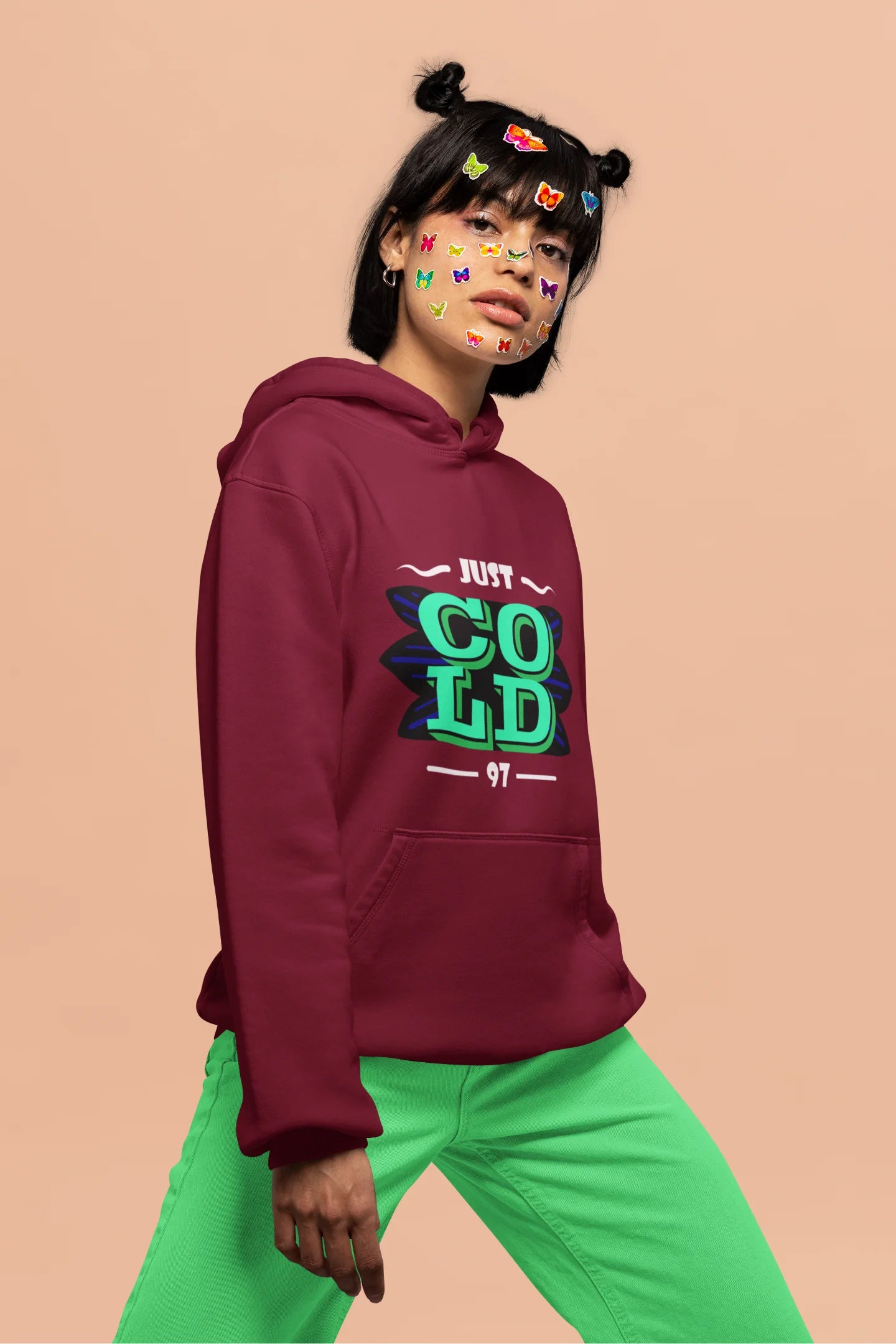 4th front view of a female model wearing an maroon sweatshirt with the text "Just Cold" printed on it.