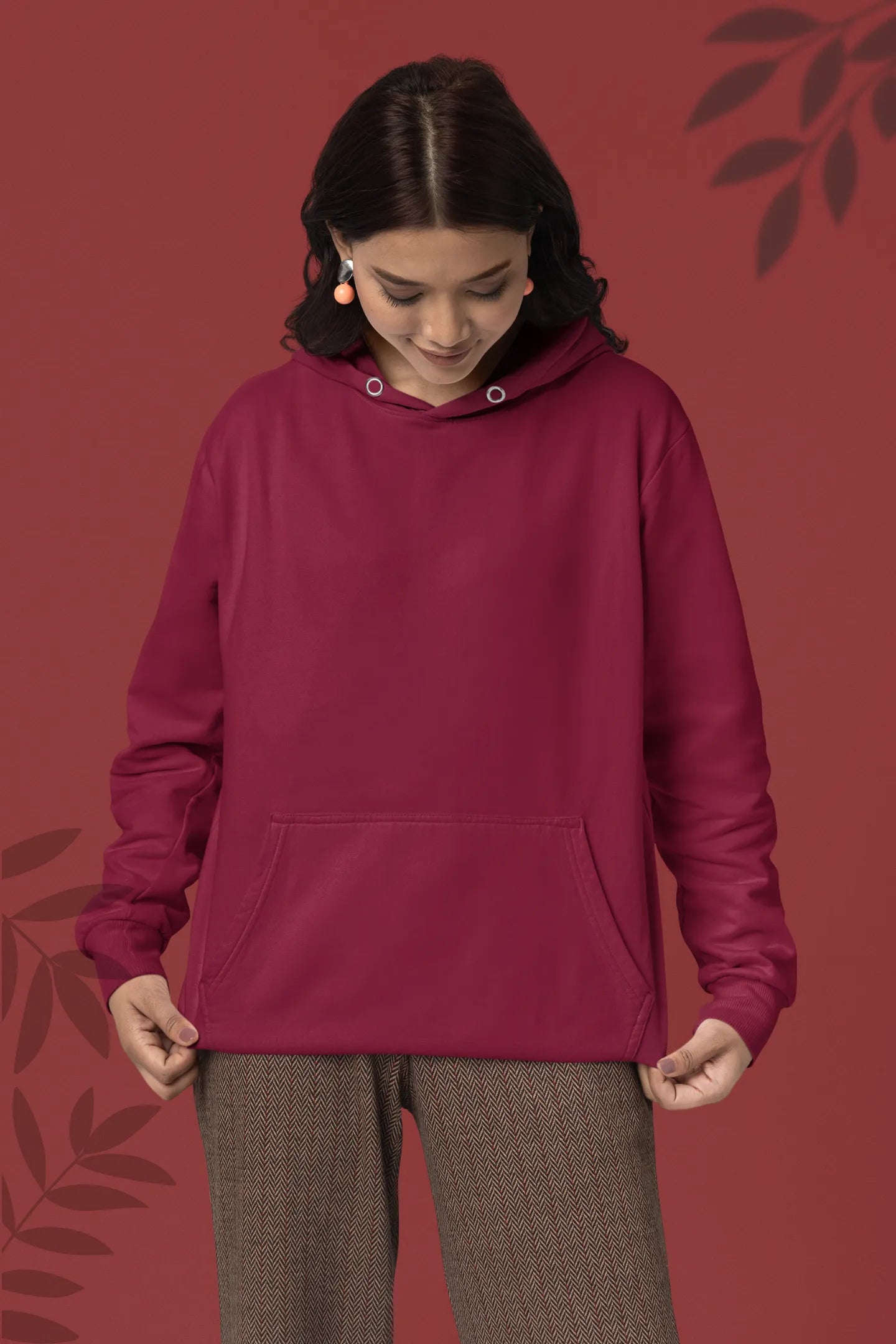 First front view of a female model wearing a maroon hoodie with a design of a wildcat sitting on ocean waves.