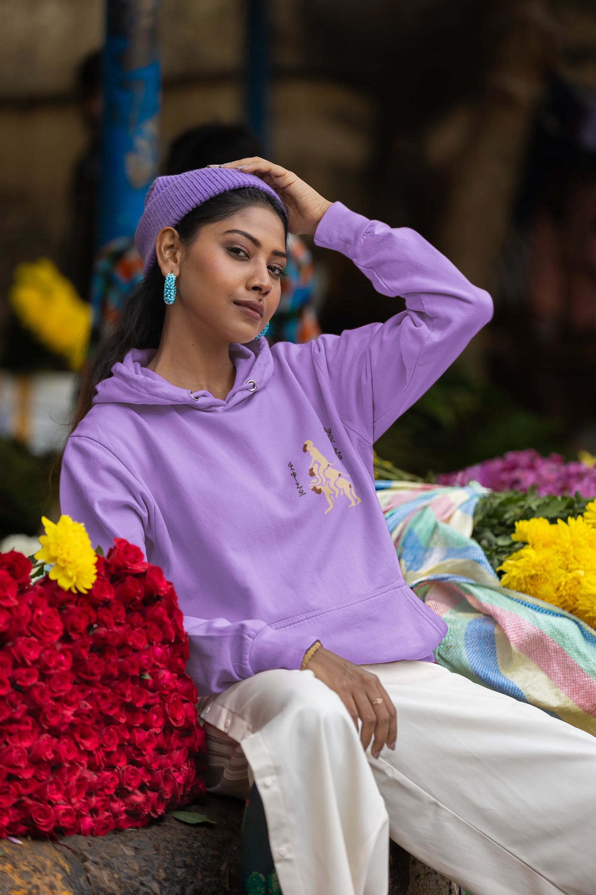 Second front view of a female model wearing a lavender hoodie with a design of the three wise monkeys: "See no evil, hear no evil, speak no evil."