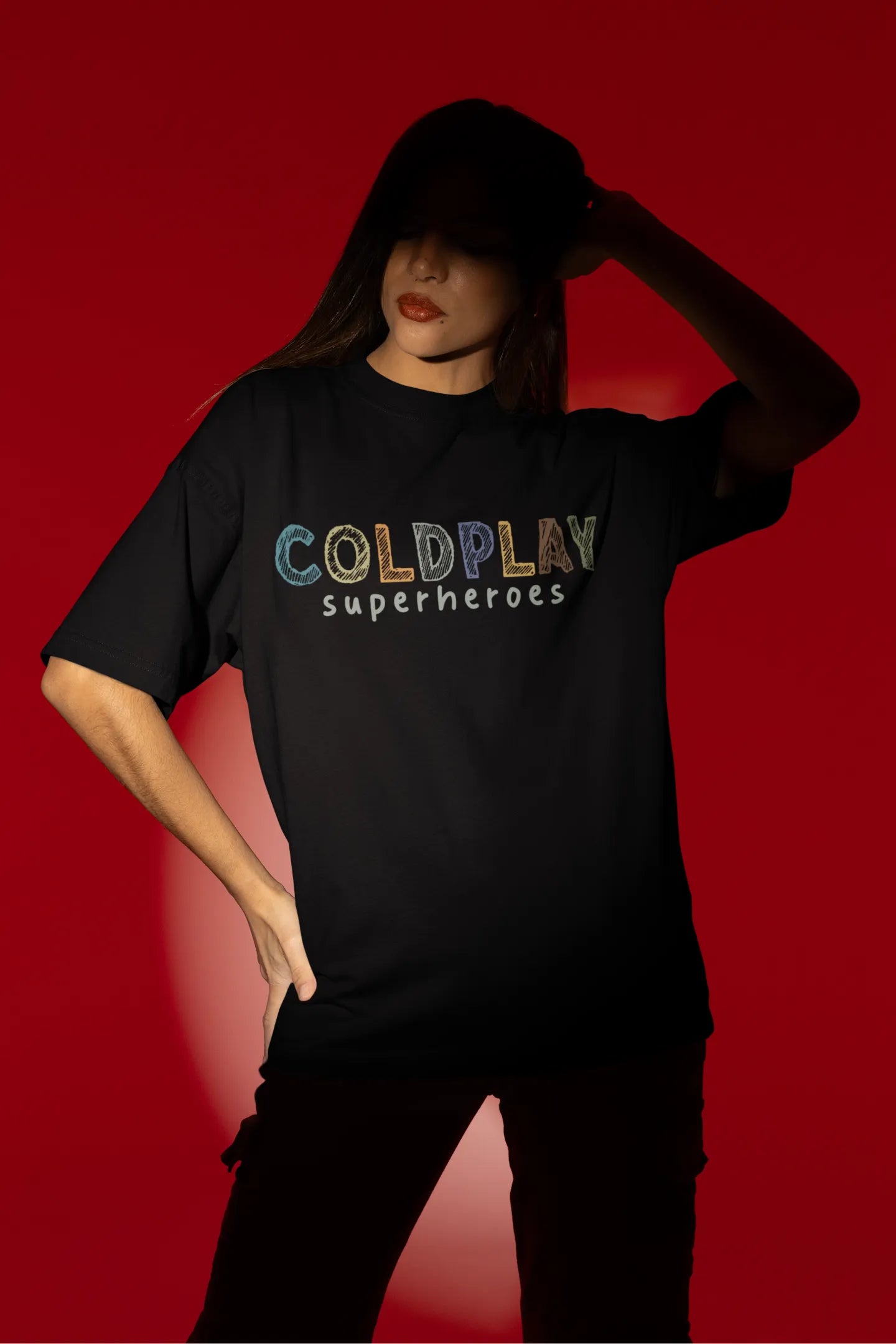 Fourth view of a female model wearing an black oversized t-shirt with a design inspired by the "Something Just Like This" music video, featuring the word "Superheroes".