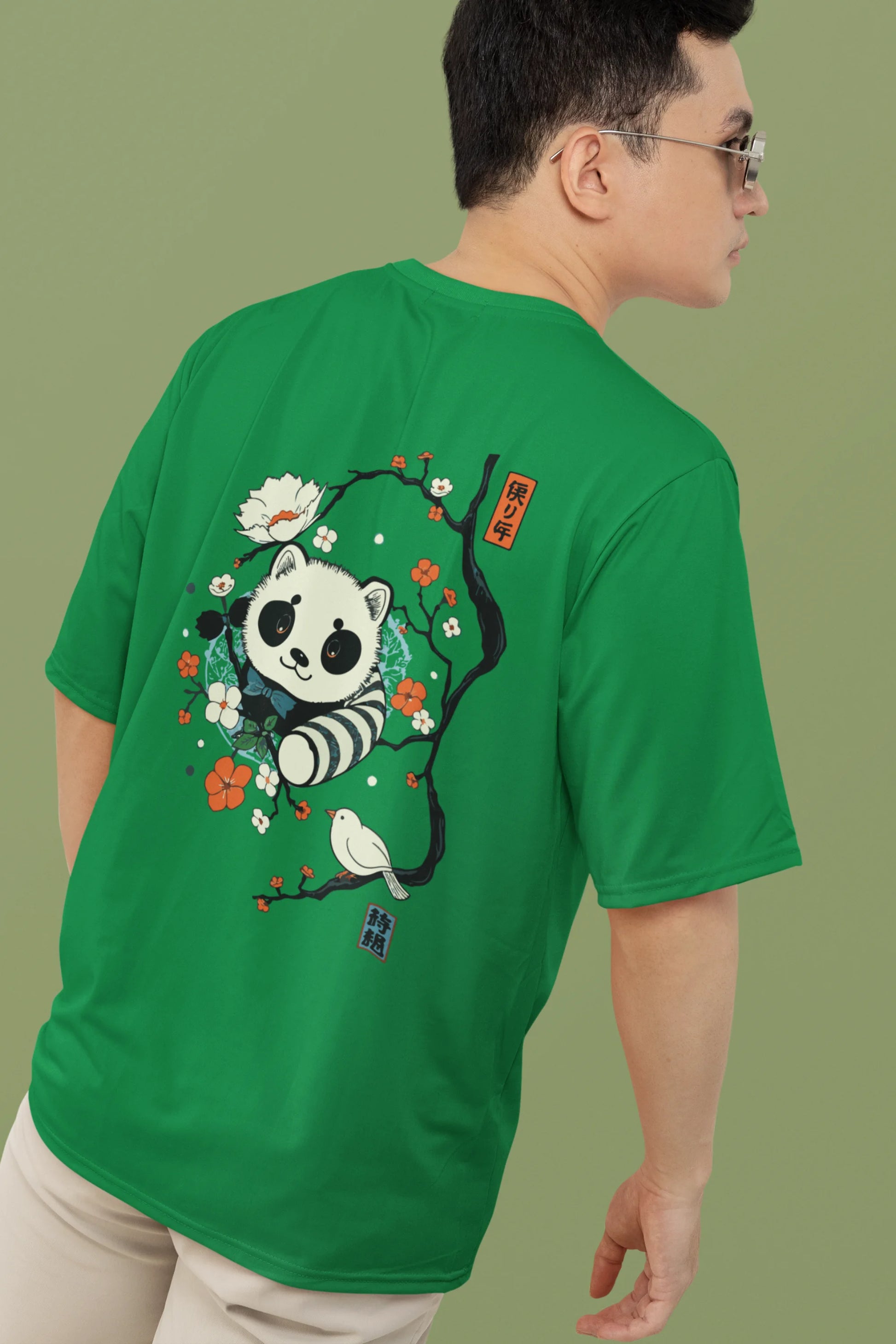 2nd back view of a male model wearing a forest green oversized tee with a panda fox surrounded by bamboo.