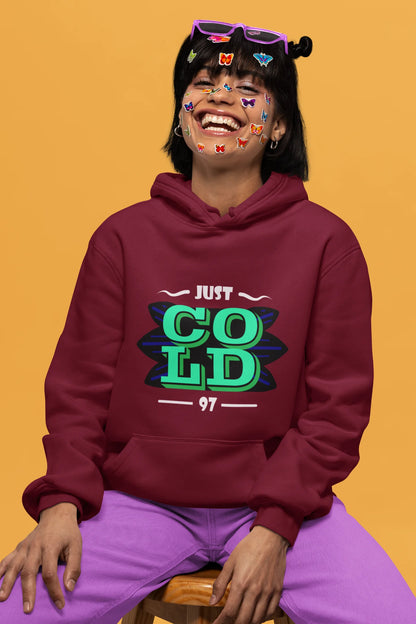 3rd front view of a female model wearing an maroon sweatshirt with the text "Just Cold" printed on it.